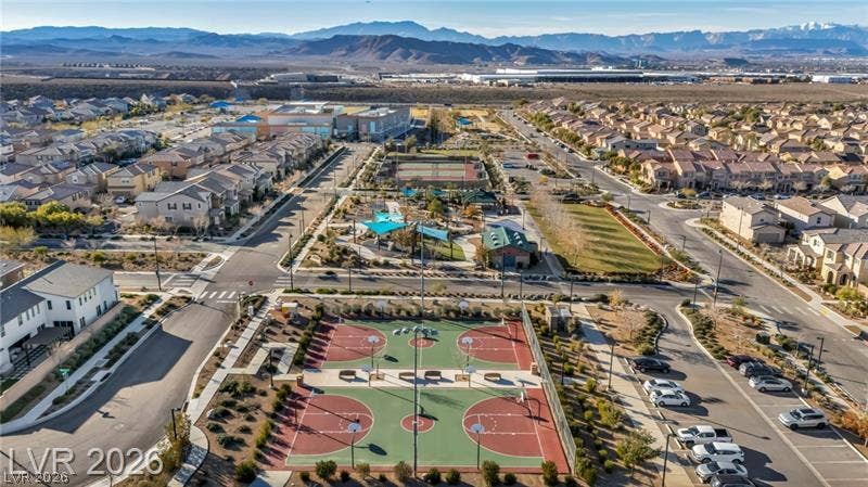 An aerial view showcases expansive community parks and basketball courts set against a mountain backdrop.