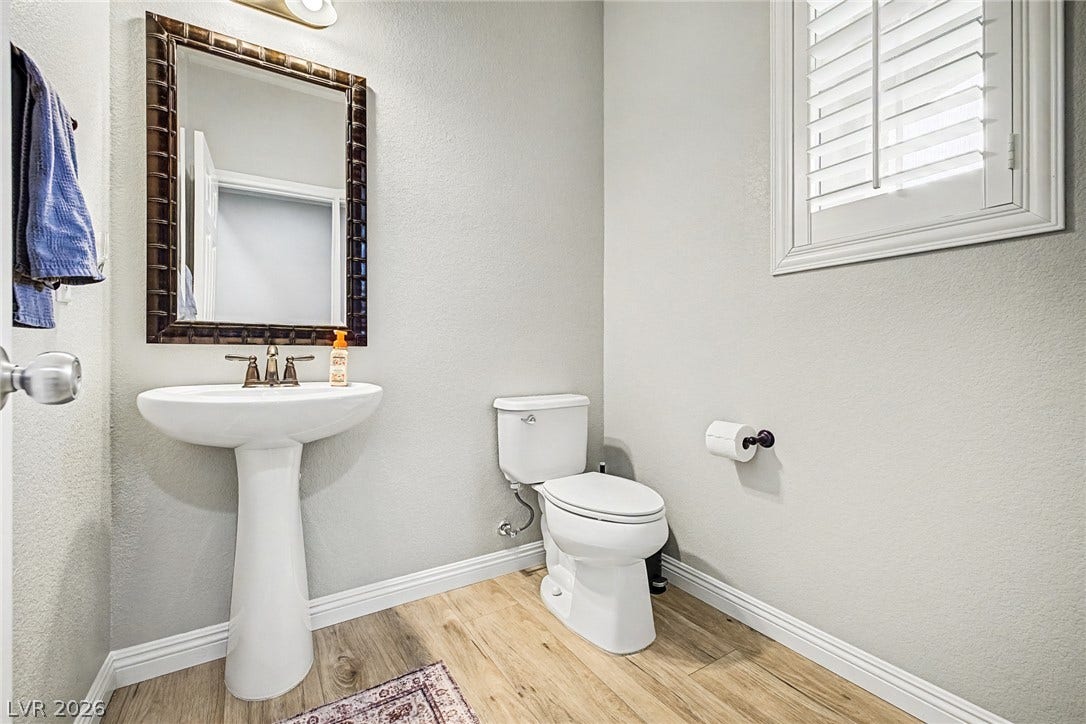A compact powder room with a pedestal sink, toilet, and a window for natural light.