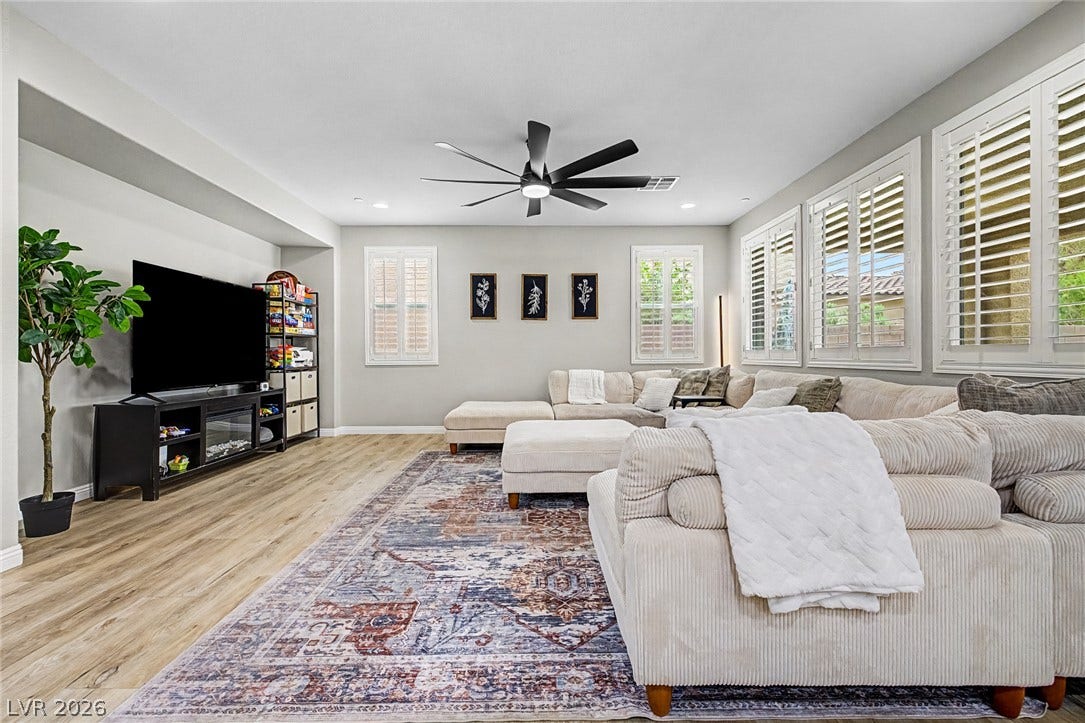 Well-lit living area features hard surface flooring, a decorative rug, and numerous windows.