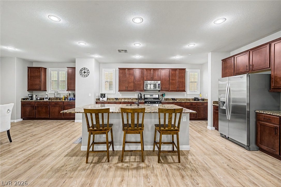 An inviting kitchen features a large central island with seating and modern stainless steel appliances.