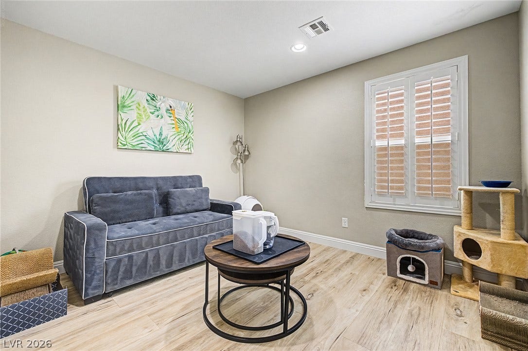 An inviting secondary living area features wood-like flooring, recessed lighting, and a well-lit window.