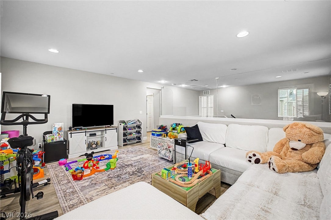 A family room, illuminated by recessed lighting, offers an inviting space for relaxation and play.