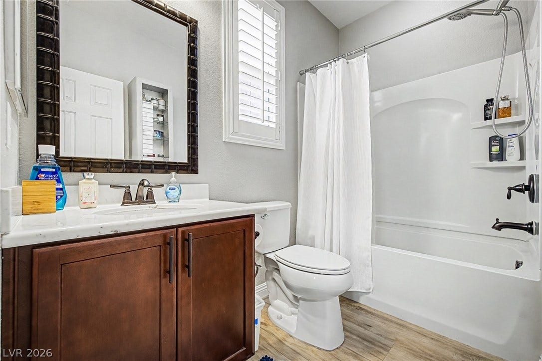 Functional full bathroom featuring a white vanity with ample storage and a complete shower-tub combination.