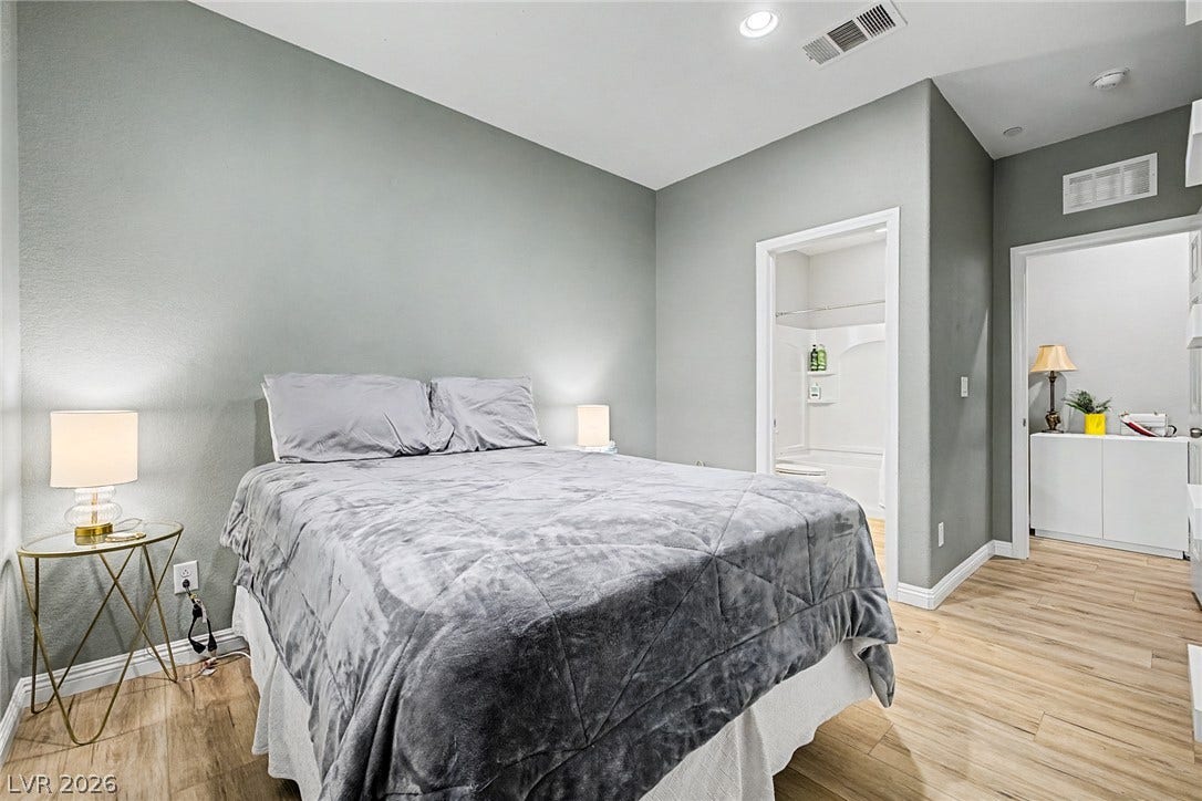 Blonde wood flooring creates a welcoming ambiance in this well-lit bedroom suite.