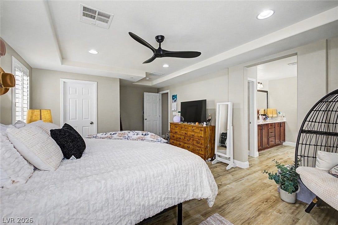 Recessed lighting illuminates this inviting bedroom featuring durable wood flooring and a refreshing ceiling fan.