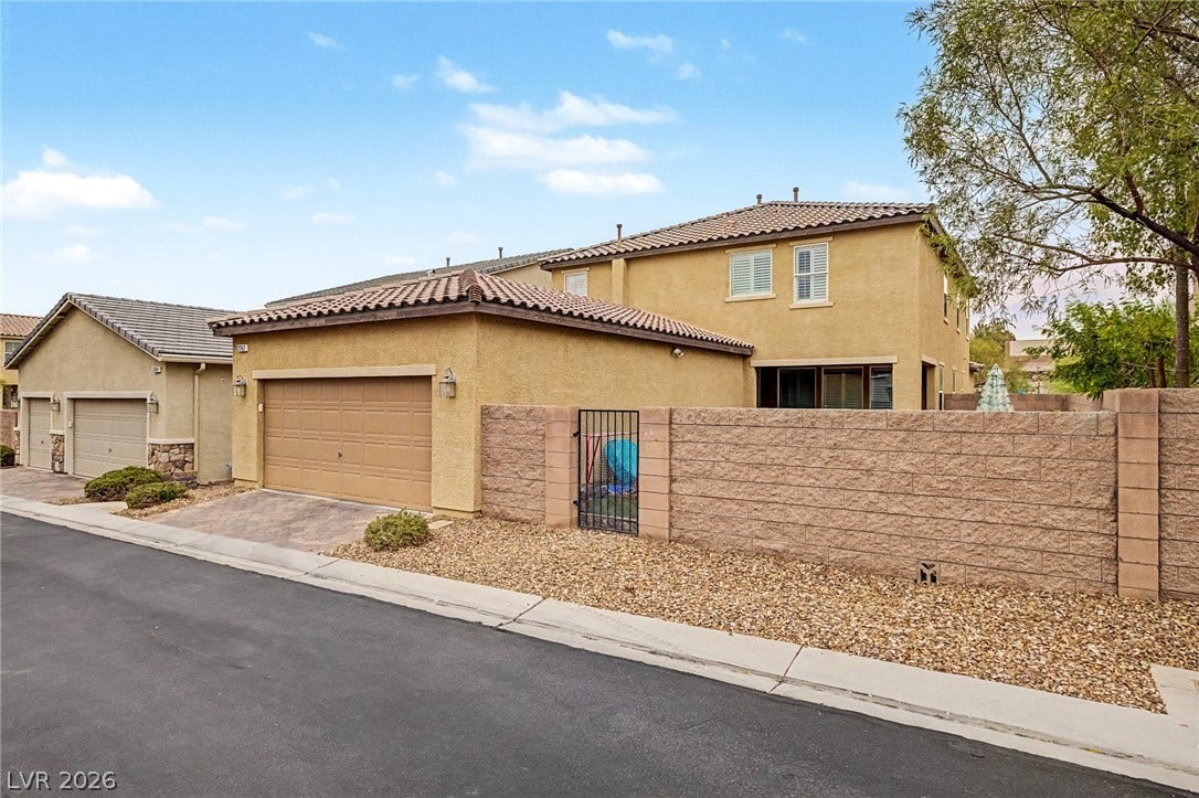 A desert-friendly landscape surrounds this stucco residence with a two-car garage and sturdy block wall.