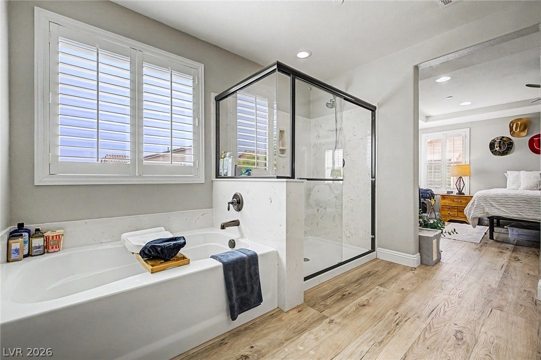 Relaxing primary bath features a spacious soaking tub and a sleek glass-enclosed shower.