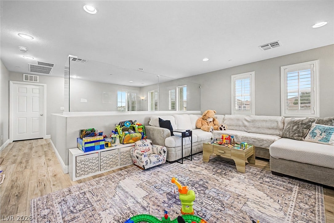 A well-lit sitting room boasts rich hardwood flooring and bright windows.