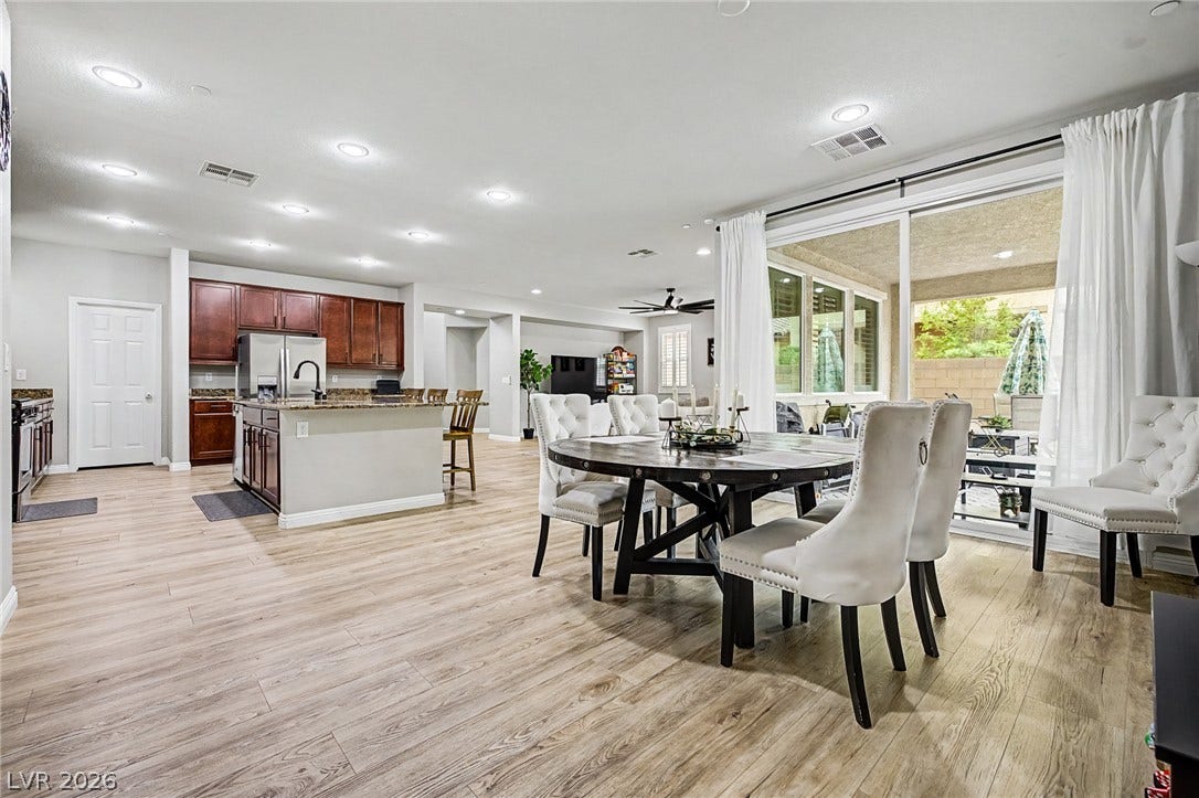 An open-concept living area boasts a modern kitchen, inviting dining space, and a generous patio accessible through sliding glass doors.