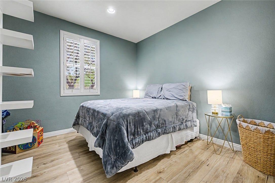 Well-lit sleeping quarters feature plantation shutters, a recessed ceiling light, and durable wood flooring.