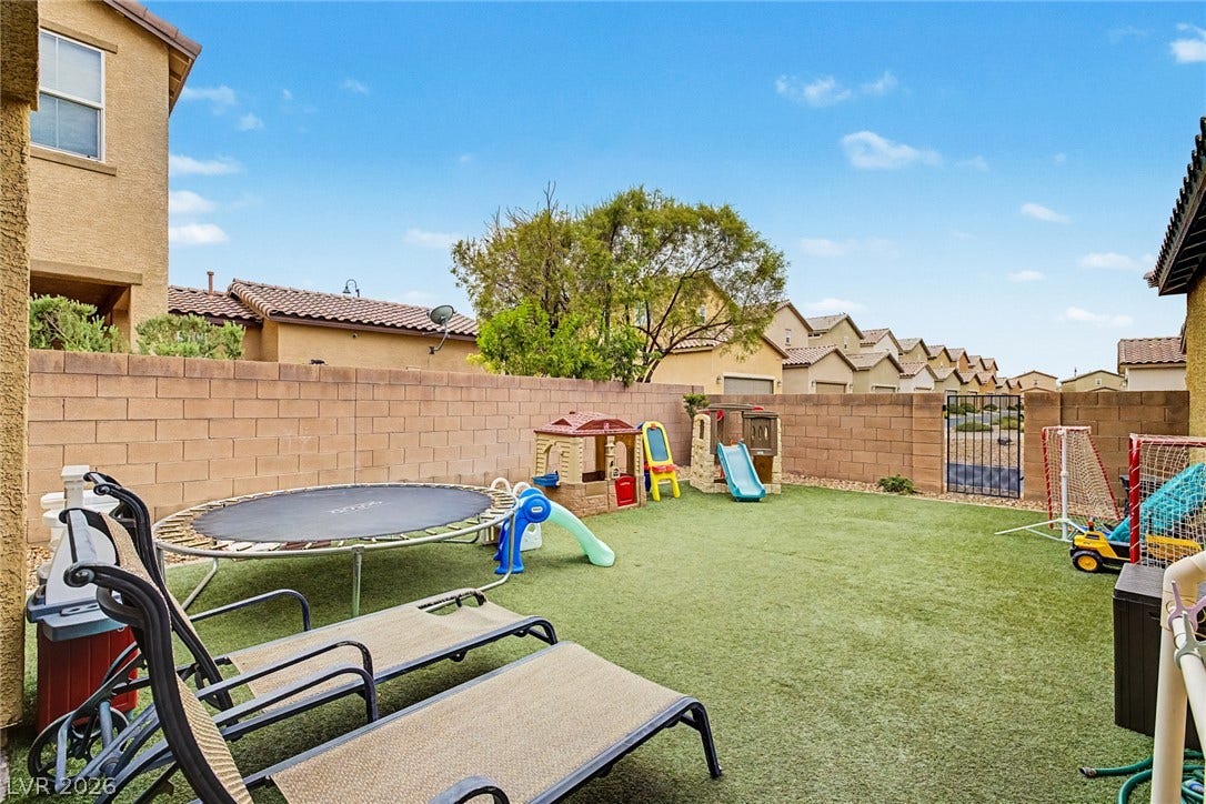 An enclosed backyard oasis features artificial turf and ample space for recreation and leisure.