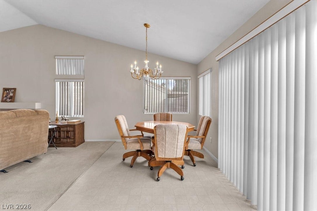 1163 Teal Point Drive, Henderson, NV 89074 Dining space with lofted ceiling, light carpet, baseboards, and an inviting chandelier