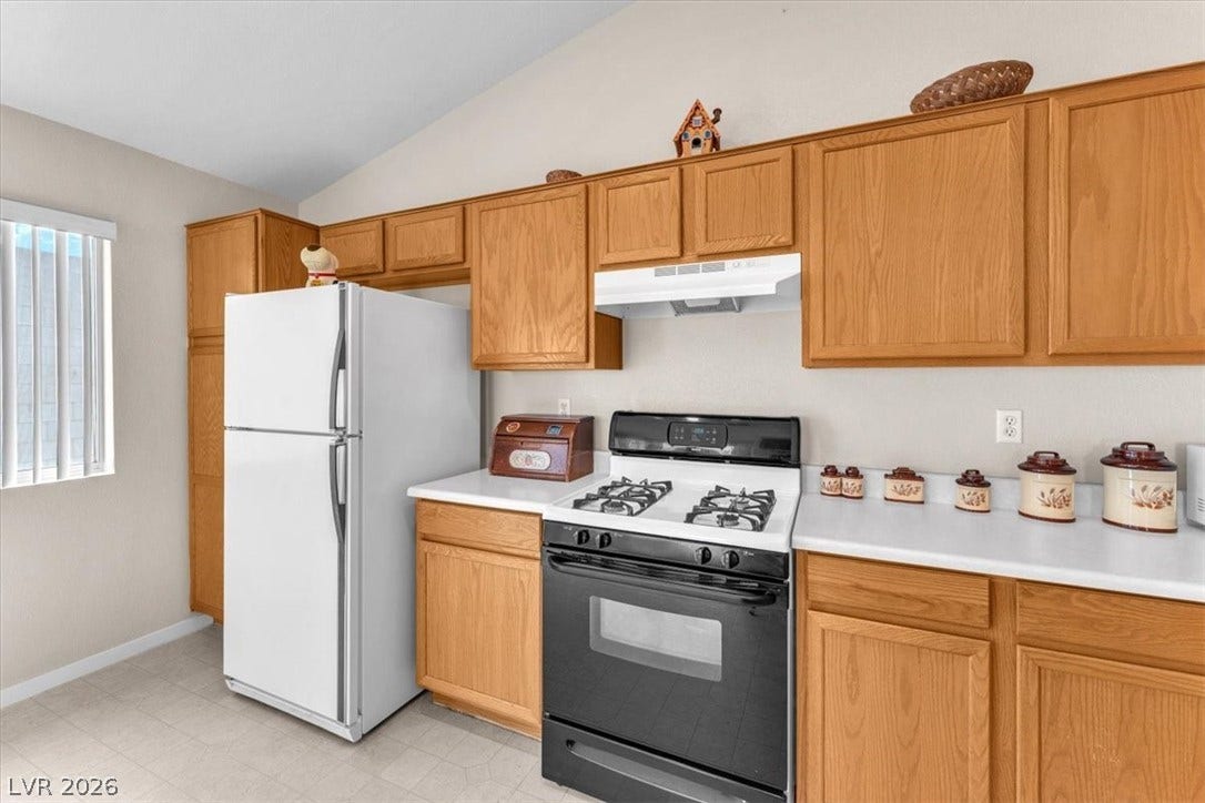 1163 Teal Point Drive, Henderson, NV 89074 Kitchen featuring under cabinet range hood, vaulted ceiling, light countertops, freestanding refrigerator, and gas range