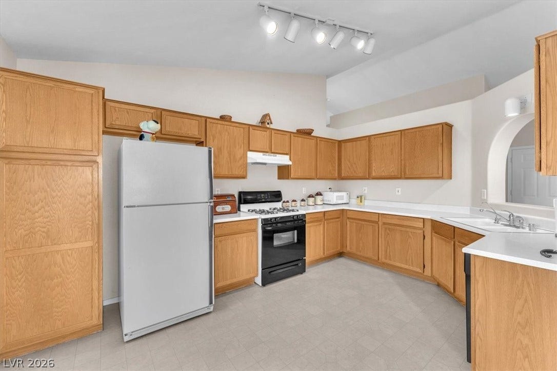 1163 Teal Point Drive, Henderson, NV 89074 Kitchen featuring under cabinet range hood, white appliances, a sink, vaulted ceiling, and light floors