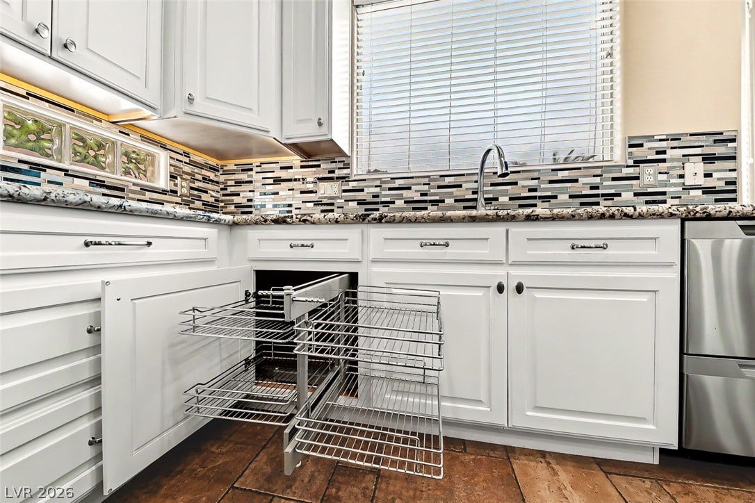 2306 Schaeffer Hills Drive, Henderson, NV 89052 A well-lit kitchen featuring elegant white cabinetry, granite countertops, and a modern tile backsplash.