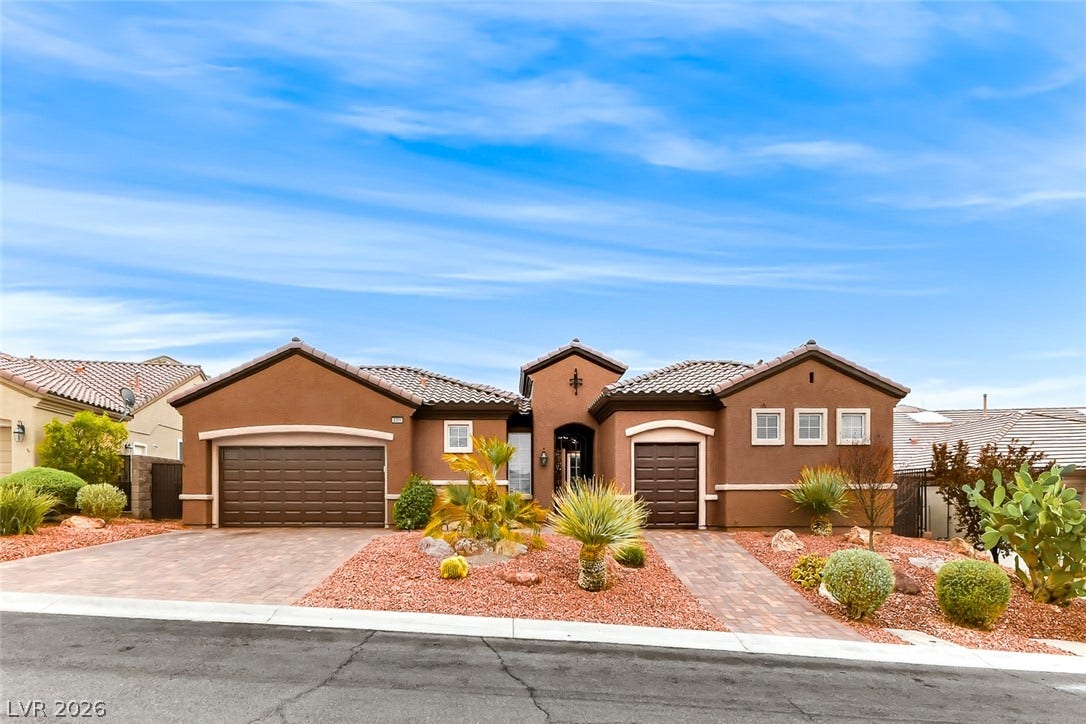 2306 Schaeffer Hills Drive, Henderson, NV 89052 A well-maintained desert landscape frames this single-story home with a tiled roof and dual garages.