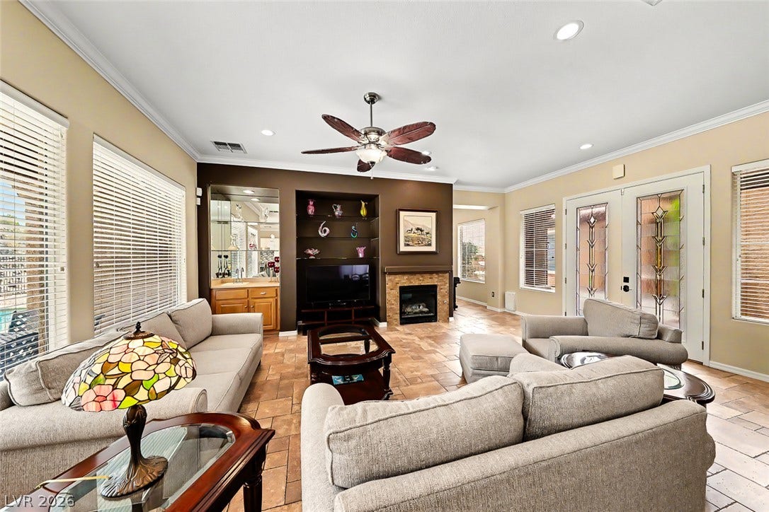 2306 Schaeffer Hills Drive, Henderson, NV 89052 A comfortable living area features a stone fireplace, built-in shelving, and direct access to outdoor spaces.