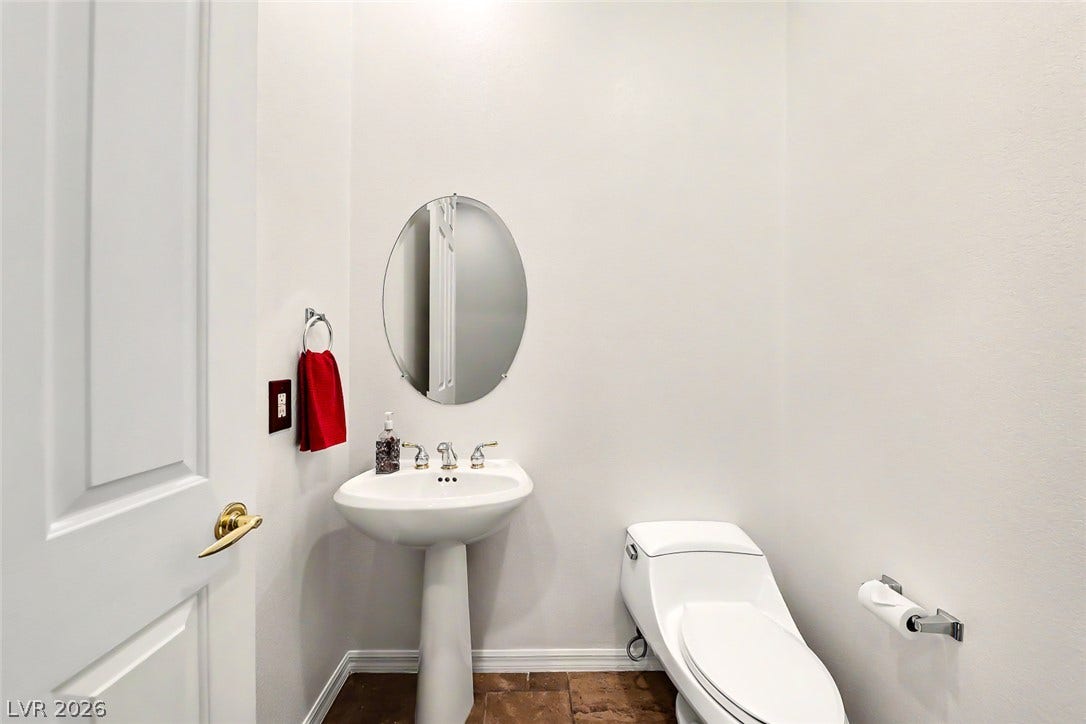 2306 Schaeffer Hills Drive, Henderson, NV 89052 A compact powder room with a sleek pedestal sink and complementary oval mirror.