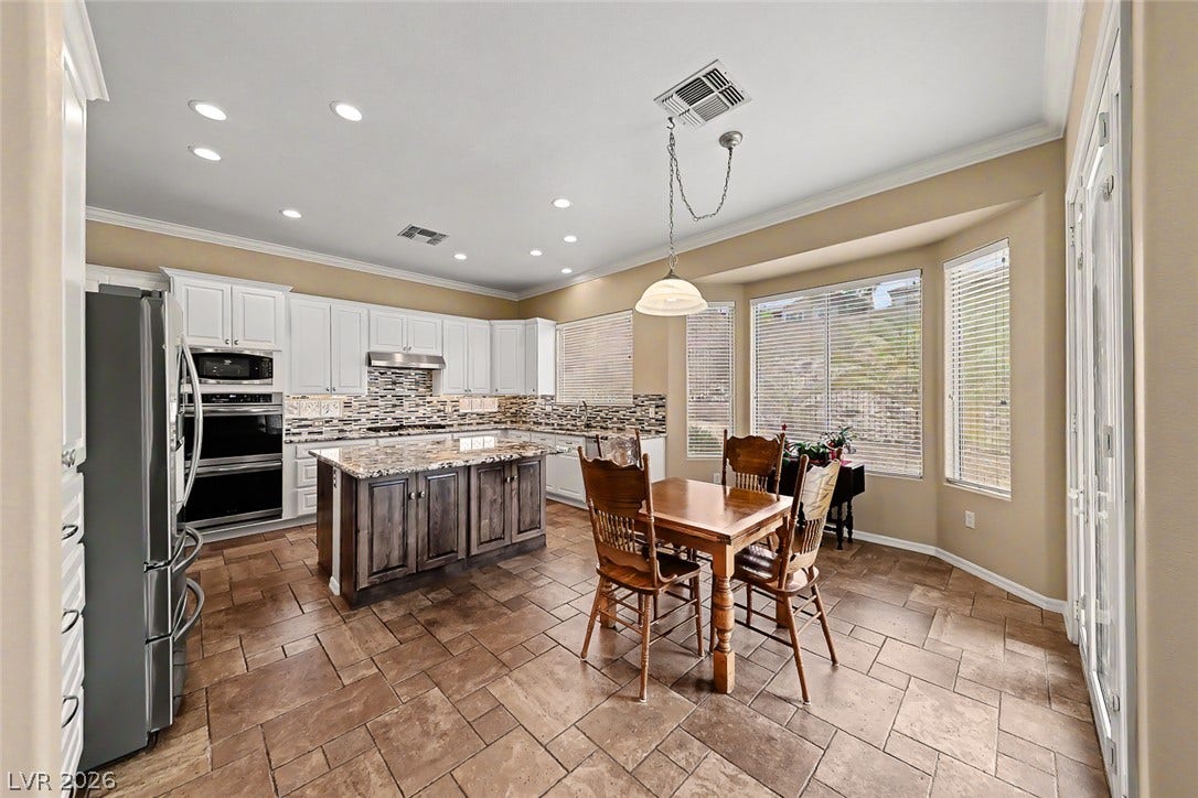 2306 Schaeffer Hills Drive, Henderson, NV 89052 A well-lit kitchen with a spacious island offers both culinary function and dining area convenience.