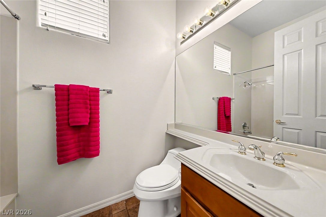 2306 Schaeffer Hills Drive, Henderson, NV 89052 A compact bathroom featuring a white toilet, vanity with a basin sink, and a shower area with a curtain rod.