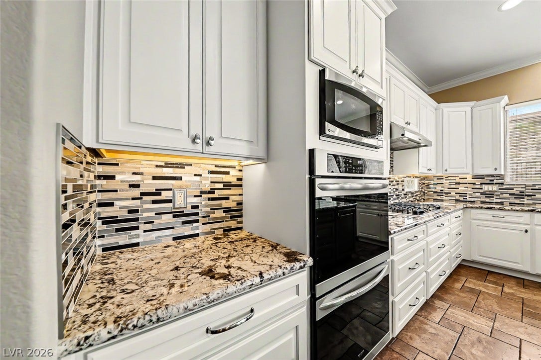 2306 Schaeffer Hills Drive, Henderson, NV 89052 White cabinetry, granite counters, and stylish tile backsplash create a functional and visually appealing kitchen.