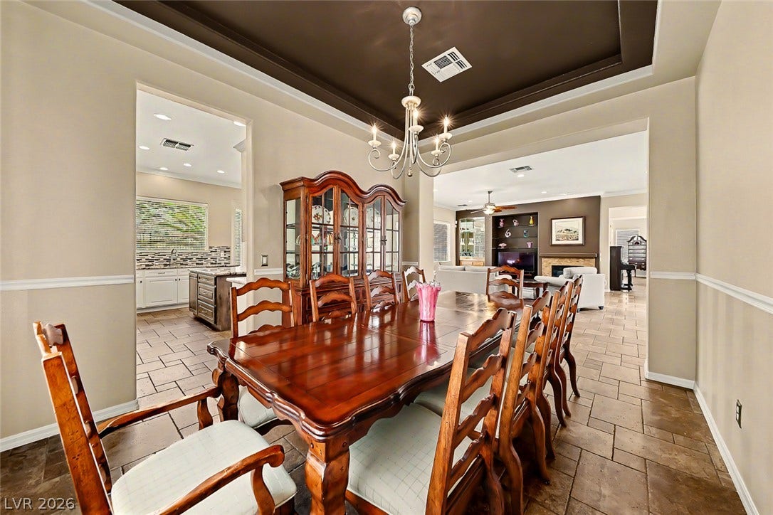 2306 Schaeffer Hills Drive, Henderson, NV 89052 A formal dining room, perfect for hosting gatherings, is illuminated by a classic chandelier and features elegant tray ceilings.