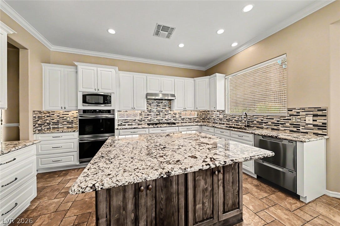 2306 Schaeffer Hills Drive, Henderson, NV 89052 A well-appointed kitchen features a spacious island with granite counters and contemporary tile flooring.