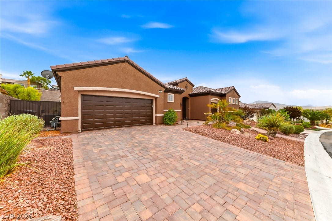 2306 Schaeffer Hills Drive, Henderson, NV 89052 A well-maintained desert landscape frames this property with an inviting paver driveway leading to a two-car garage.