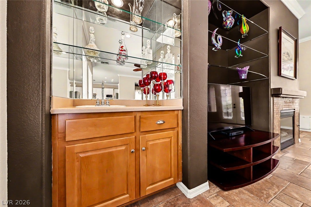 2306 Schaeffer Hills Drive, Henderson, NV 89052 A well-appointed wet bar with mirrored shelving and a built-in fireplace create a sophisticated entertainment space.