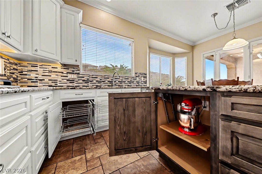 2306 Schaeffer Hills Drive, Henderson, NV 89052 Well-appointed kitchen features abundant cabinetry, durable granite countertops, and mosaic tile backsplash, perfect for culinary adventures.