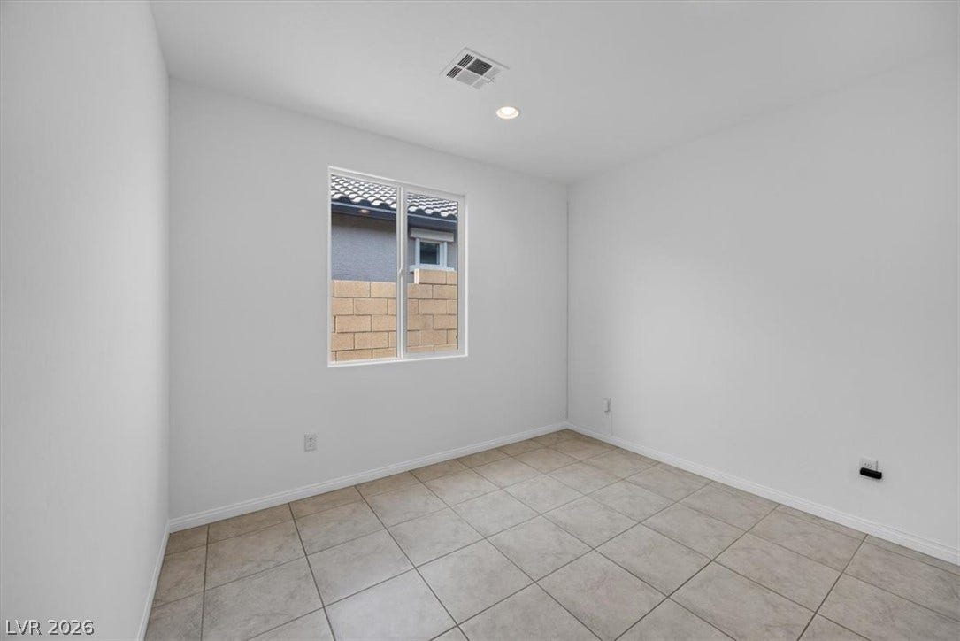 A well-lit room featuring durable tile flooring and a bright window.