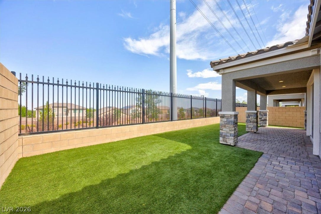 A private yard with artificial turf and a covered patio offers ideal outdoor living.