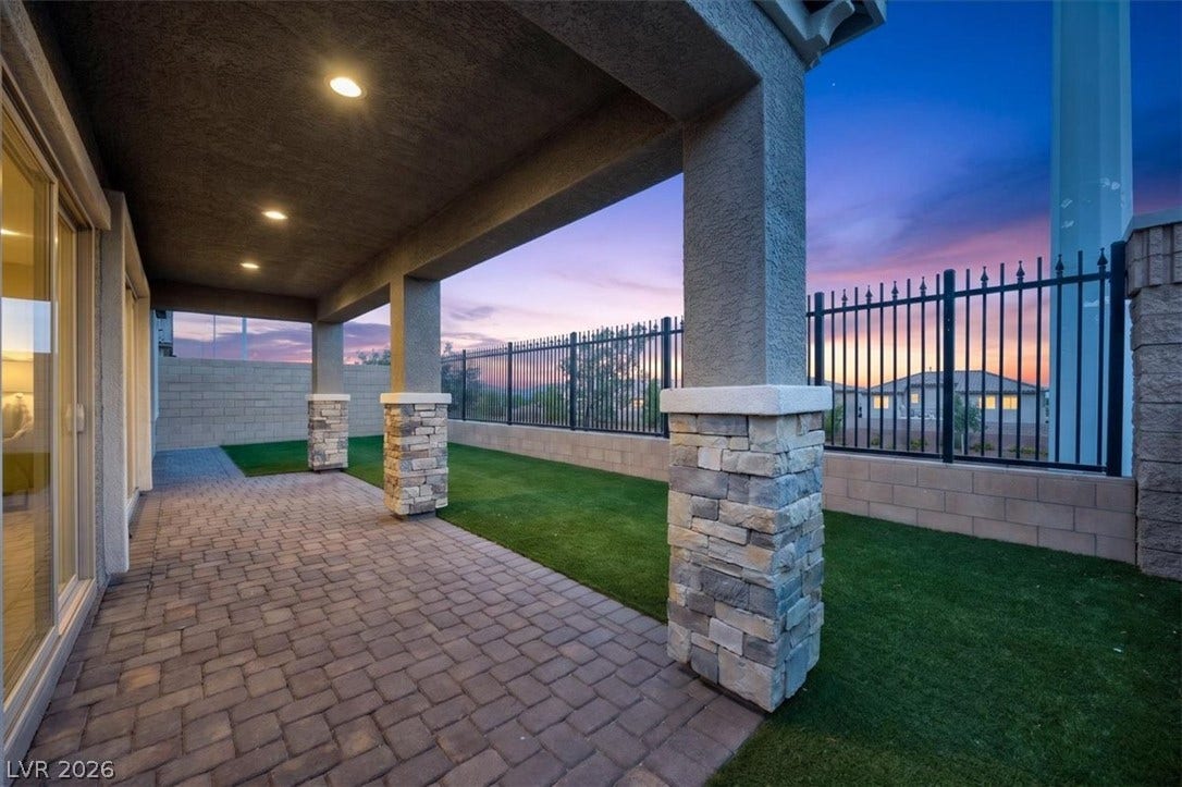 A spacious covered patio offers a perfect outdoor retreat, complete with decorative stone pillars and a paver floor.