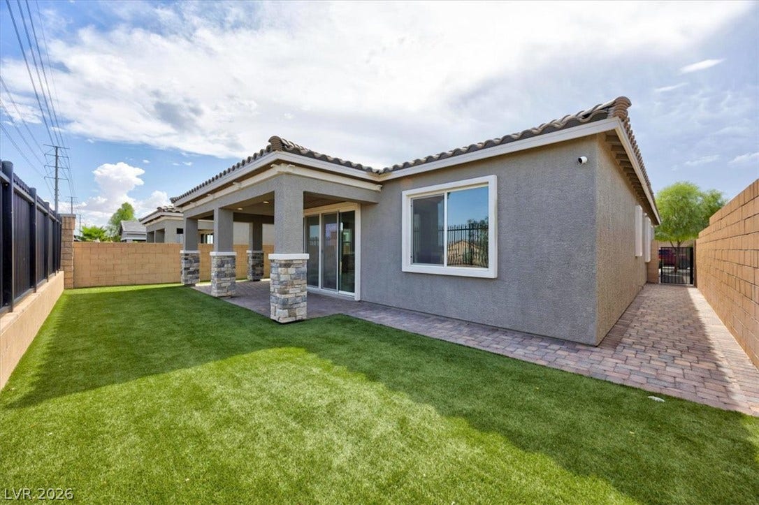 A private backyard oasis features lush artificial turf and a covered patio, perfect for outdoor enjoyment.