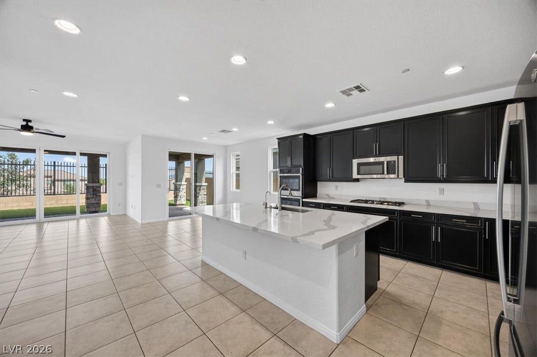 The chef's dream kitchen with an island, a gas range, and stainless steel appliances flows seamlessly into a spacious living area.