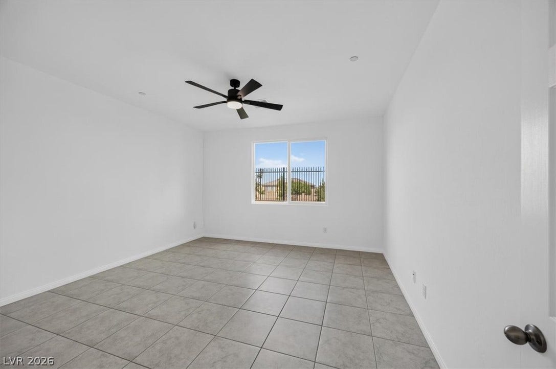 A well-lit room featuring clean tiled flooring and a modern ceiling fan for comfort.