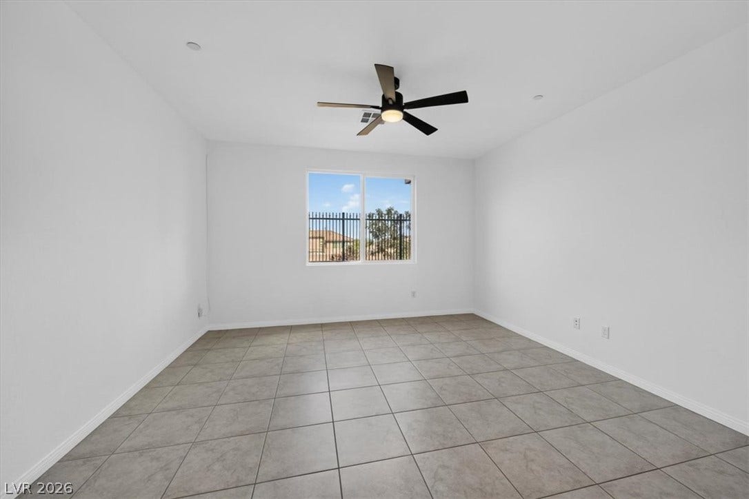 A well-lit bedroom features cool tile flooring and a ceiling fan for comfort.