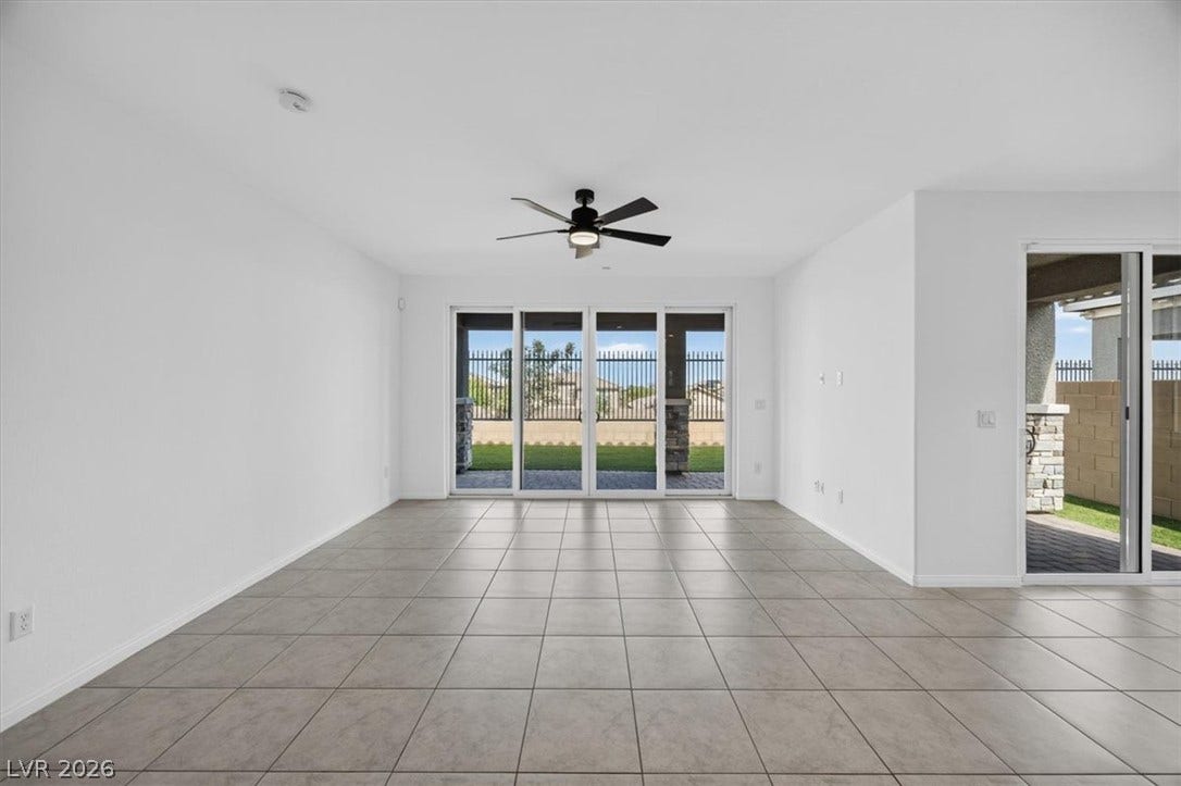Sliding glass doors offer seamless indoor-outdoor living from this spacious room with tiled flooring and a ceiling fan.