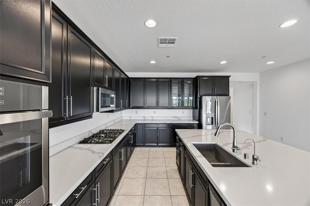 Culinary delights await in this modern kitchen, featuring sleek dark cabinetry and luminous countertops.