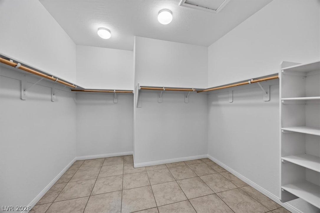 A generously sized walk-in closet with ample storage solutions and tiled flooring for effortless maintenance.