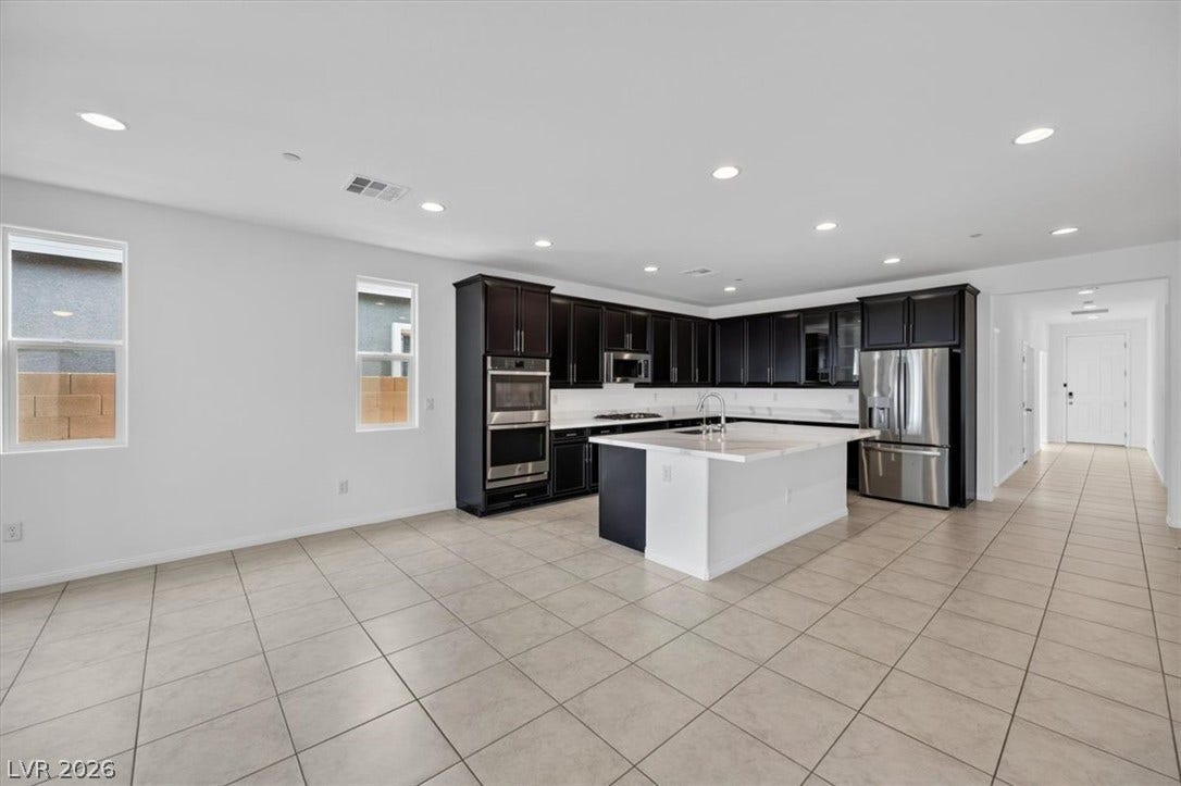 An open-concept living space highlights a sophisticated kitchen with a substantial island and gleaming stainless steel appliances.