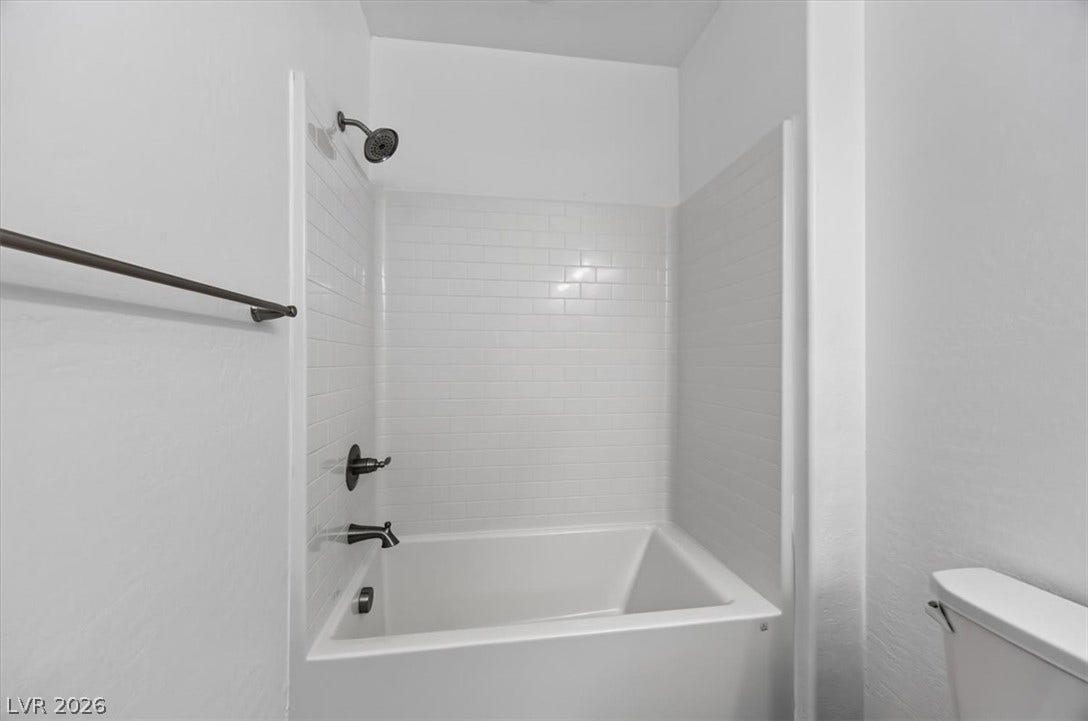 A well-maintained tub-shower combination features subway tile surround and contemporary dark bronze fixtures.