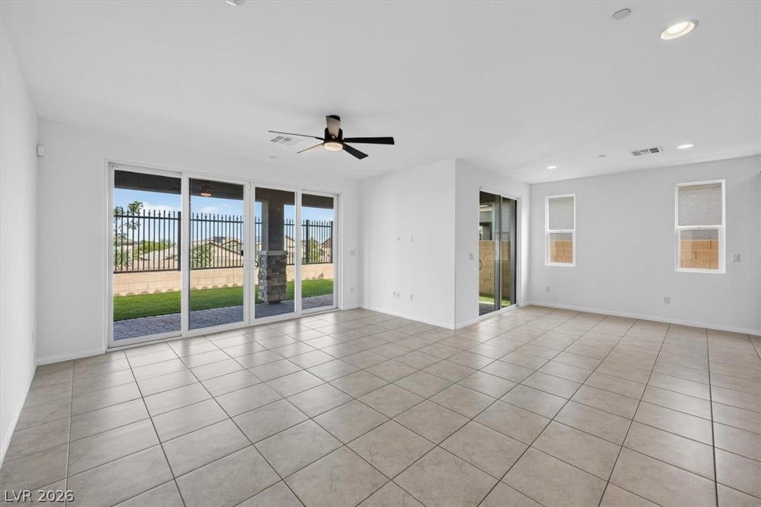 A spacious room offers ample natural light and direct backyard access through large glass sliding doors.
