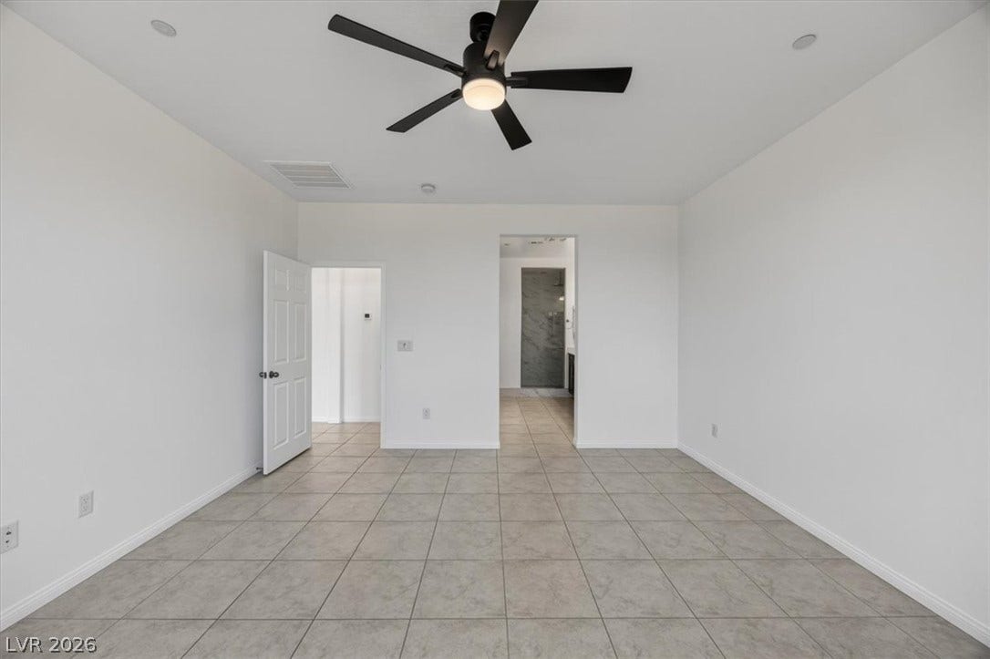 A well-lit bedroom features cool tile flooring and a ceiling fan for comfort.