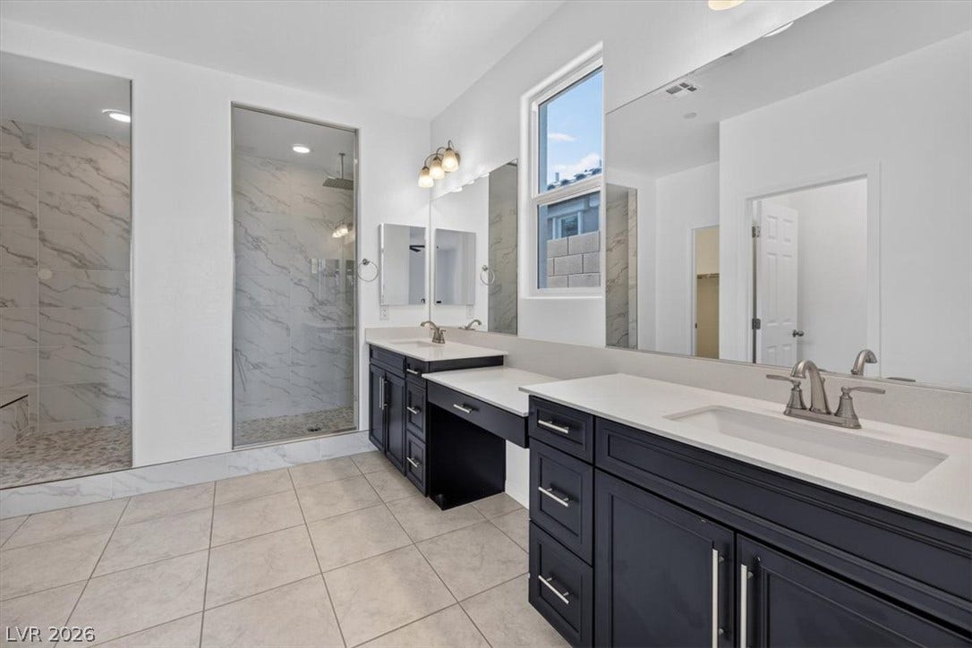A well-appointed primary bathroom showcases dual vanities, an expansive shower, and ample counter space.
