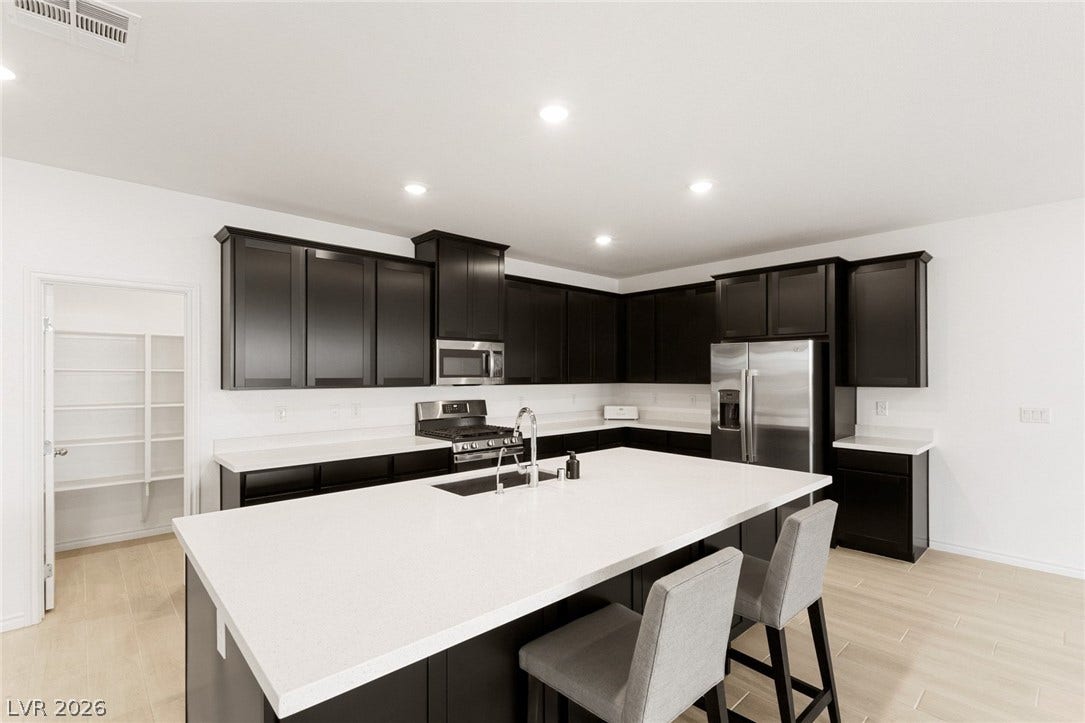 9986 Joshua Foothills Street, Las Vegas, NV 89178 A well-appointed kitchen features dark cabinetry, white countertops, stainless steel appliances, and a convenient pantry.