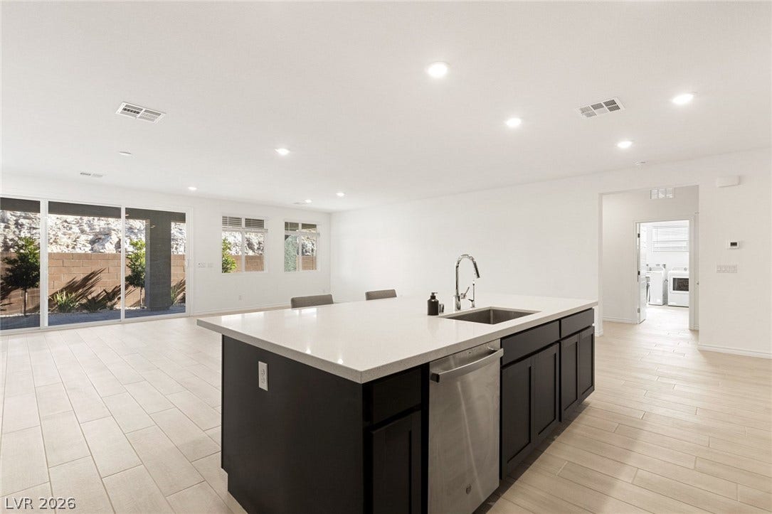 9986 Joshua Foothills Street, Las Vegas, NV 89178 A contemporary open-concept kitchen features a spacious island with a sink, extending into a naturally illuminated living area.