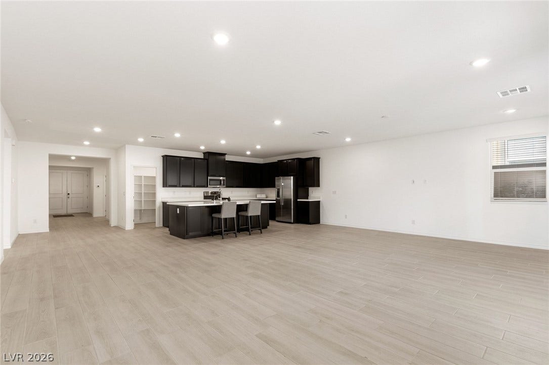 9986 Joshua Foothills Street, Las Vegas, NV 89178 An open-concept living area features sleek dark cabinetry, white countertops, and modern light wood flooring throughout.