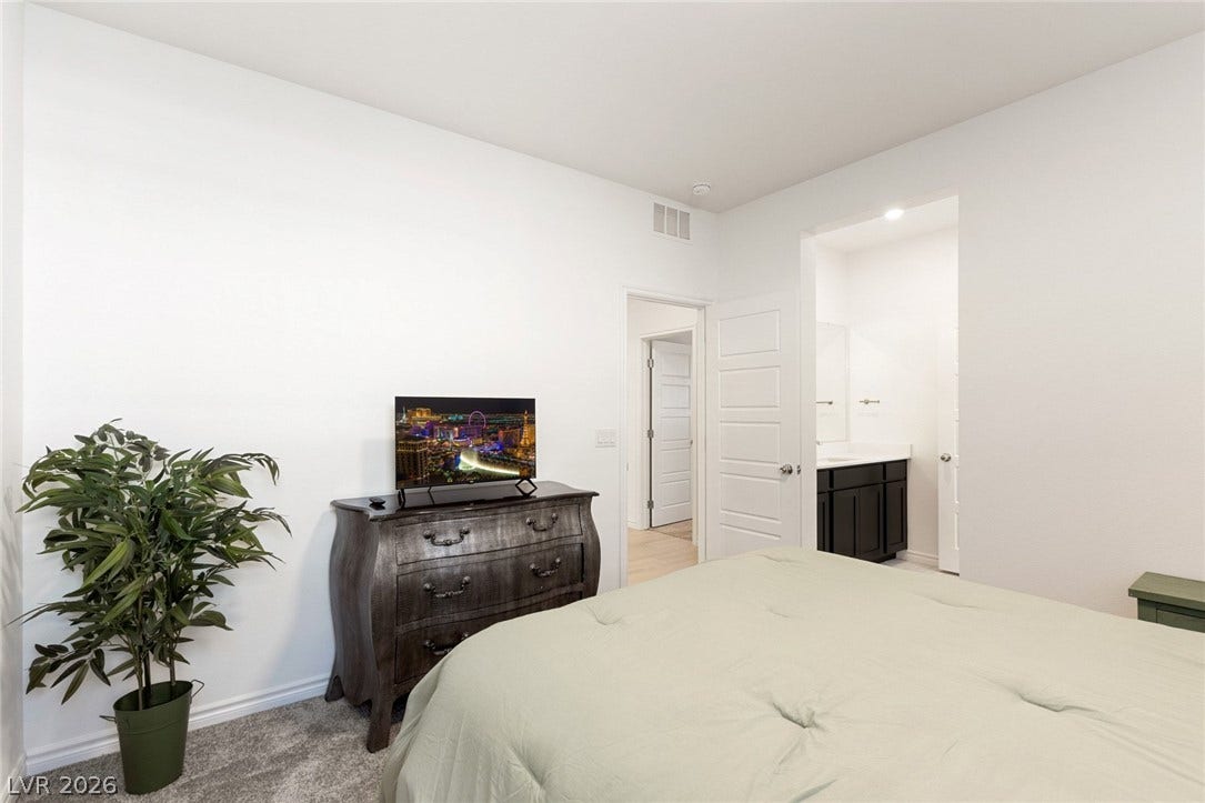 9986 Joshua Foothills Street, Las Vegas, NV 89178 Comfortable bedroom retreat with plush carpeting and convenient access to an en-suite bathroom.