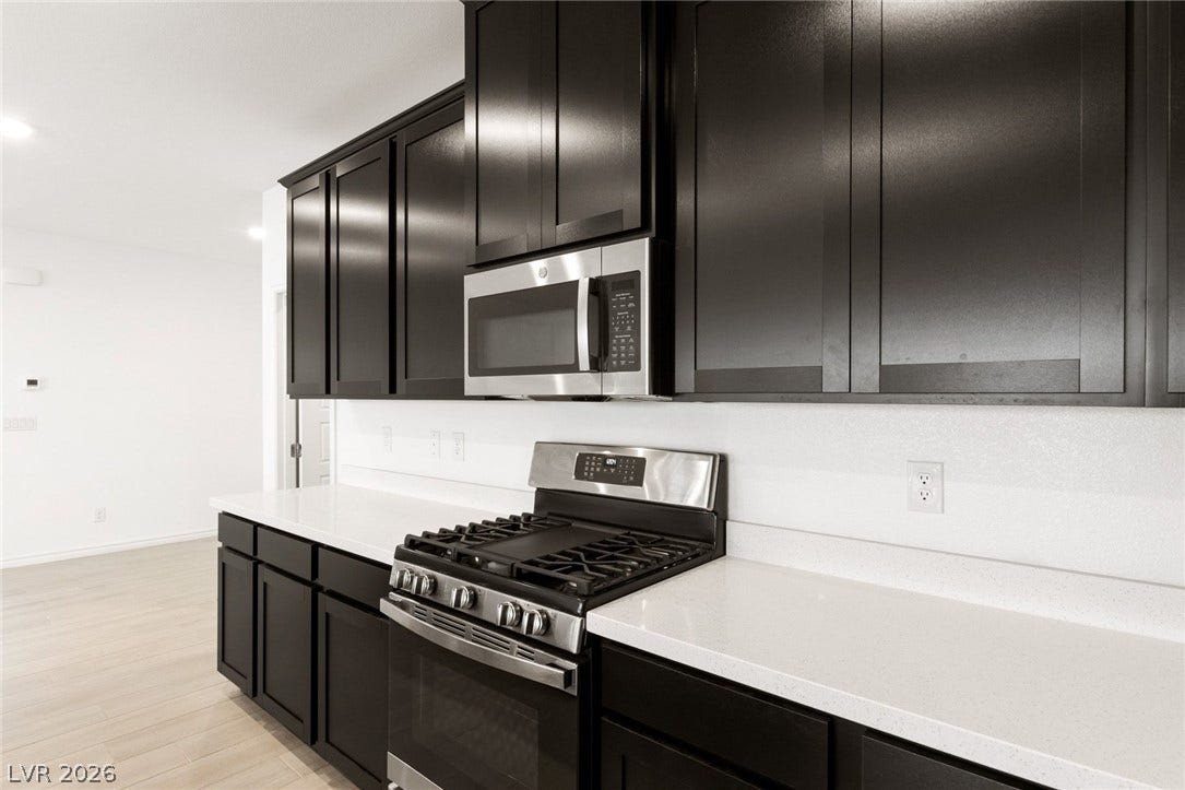 9986 Joshua Foothills Street, Las Vegas, NV 89178 A well-appointed kitchen showcasing contemporary dark cabinetry and pristine white countertops.